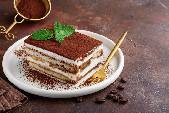 Tiramisu traditionnel au cacao avec biscuits imbibés, menthe fraîche sur assiette blanche